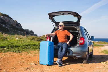Seyahat, tatil, yaz gezisi ve insanlar kavramı - adam bavul bir arabanın içinde tatil oluyor