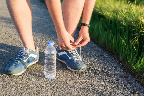 Zapatos para correr. Las zapatillas descalzas se cierran. atleta masculino atando cordones para trotar en la carretera. Corredores listos para entrenar. Estilo de vida deportivo . —  Fotos de Stock