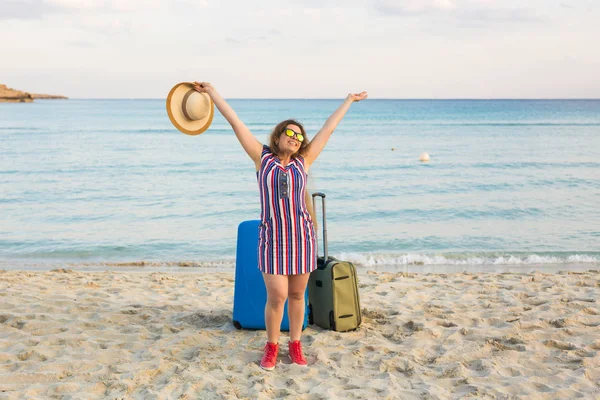 Strand, vakantie, vakantie en geluk Concept - jonge vrouw lachend in de buurt van de zee met haar Bagage — Stockfoto
