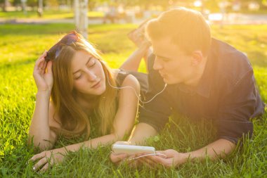 Genç güzel çift veya birlikte çimlere uzanmış, Müzik Koleji Öğrencileri. Aşk, ilişki, yaz ve yaşam tarzı kavramı