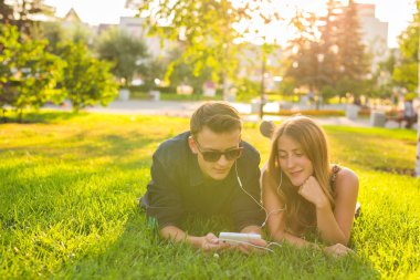 Genç güzel çift veya birlikte çimlere uzanmış, Müzik Koleji Öğrencileri. Aşk, ilişki, yaz ve yaşam tarzı kavramı