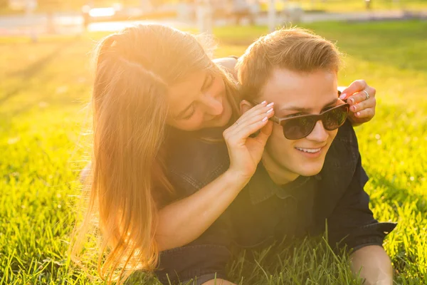 Jovem casal se divertindo e jogando na grama. mulher deitada sobre seu amante, sorrindo — Fotografia de Stock