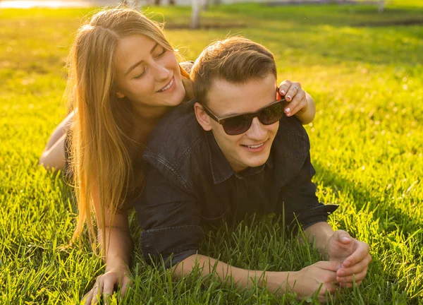 Молода пара розважається і грає в траві. жінка лежить над коханкою, посміхаючись — стокове фото