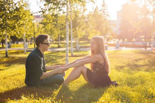 La amistad, el ocio, el verano y el concepto de la gente - joven pareja de amor sentado en la hierba en el parque —  Fotos de Stock