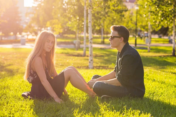 Дружба, дозвілля, літо і люди концепція молода пара кохання сидить на траві в парку — стокове фото