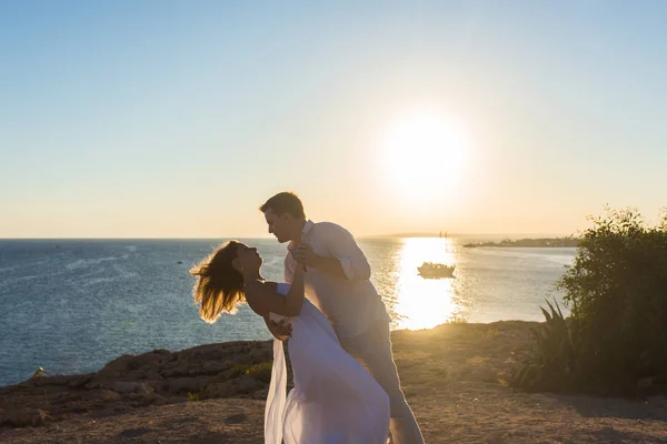 Casal abraçando e beijando uns aos outros na praia contra o oceano — Fotografia de Stock