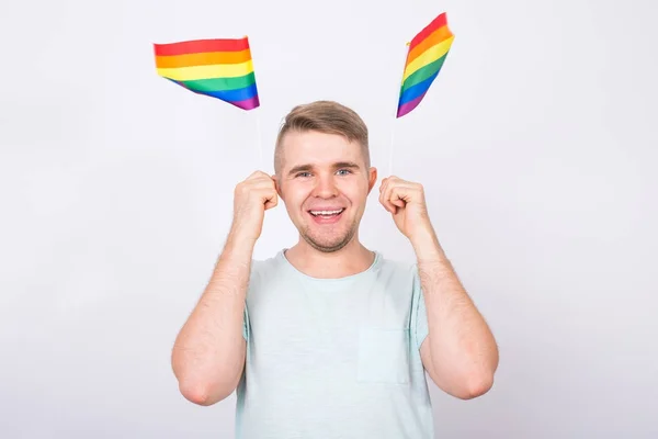 Macho divertido de pé com a mão segurando as bandeiras do arco-íris. Conceito de minoria sexual e LGBT — Fotografia de Stock