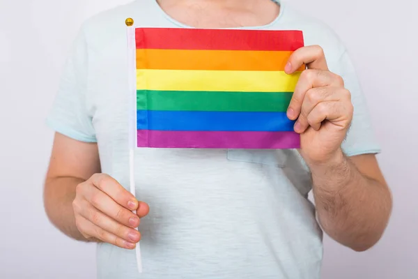 Homem segurando a bandeira do arco-íris de perto. Conceito de minoria sexual e LGBT — Fotografia de Stock