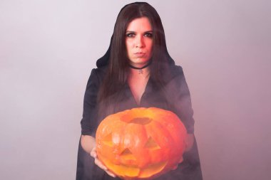 Halloween cadı bir turuncu kabak Jack o fener duman ile tutarak