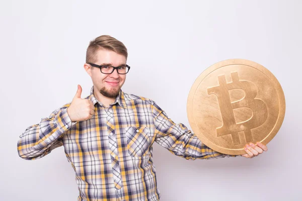 Feliz joven alegre sosteniendo gran bitcoin de oro sobre fondo blanco. Cripto moneda, dinero virtual, internet y concepto de economía — Foto de Stock