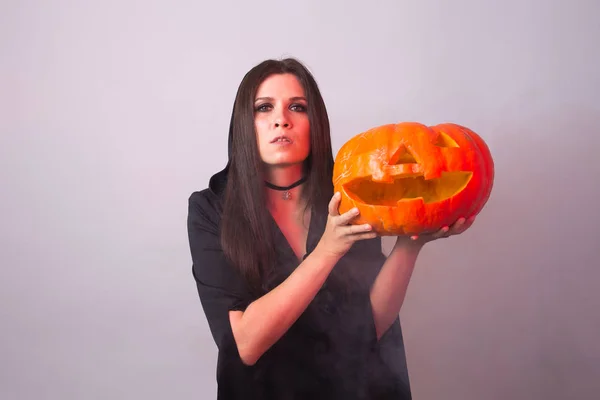 Ведьма на Хэллоуин держит оранжевую тыкву Джек о Фонарь с дымом — стоковое фото