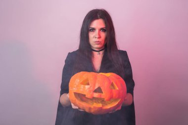 Halloween cadı bir turuncu kabak Jack o fener duman ile tutarak