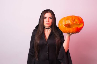 Kadın cadı olarak stüdyoda kabak ile duruyor. Cadılar Bayramı ve karnaval kavramı