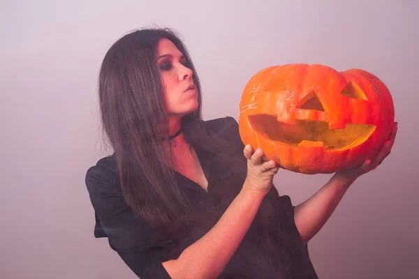 Femme comme sorcière est debout avec la citrouille dans le studio. Halloween et concept de carnaval — Photo