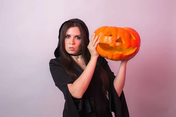 Femme comme sorcière est debout avec la citrouille dans le studio. Halloween et concept de carnaval — Photo