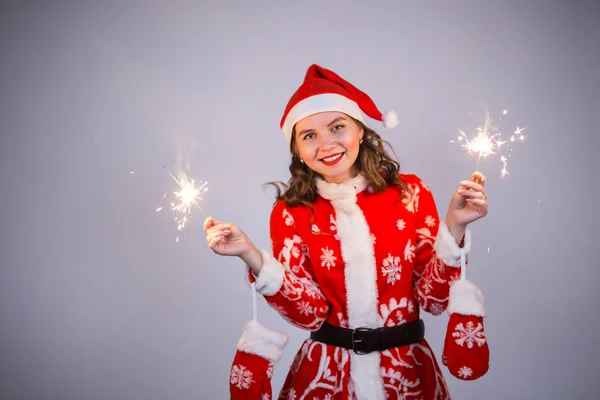 Junge Weihnachtsfrau in rotem Weihnachts- oder Neujahrsmantel und Hut mit Wunderkerze und Bengalfeuer. — Stockfoto