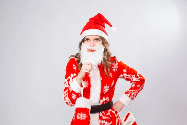 Забавная девушка в костюме Санта-Клауса и с бородой на белом фоне. Концепция праздников, шуток и людей — стоковое фото