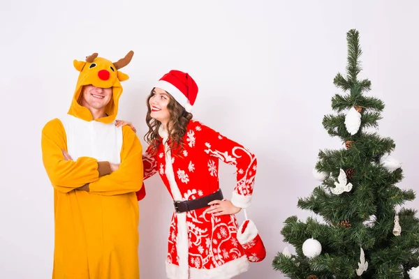 Счастливая молодая женщина в шляпе Санта Клауса и мужчина в карнавальном костюме оленя. Веселье, праздник, шутка и смех — стоковое фото
