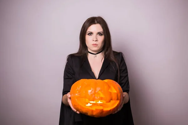 Woman as witch is standing with the pumpkin in the studio. Halloween and carnival concept — Stock Photo, Image