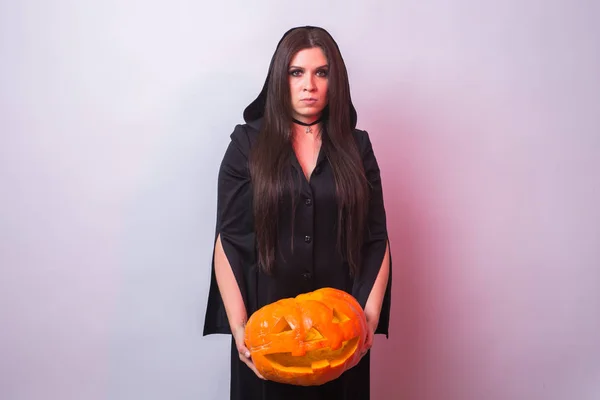 Женщина как ведьма стоит с тыквой в студии. Концепция Хэллоуина и карнавала — стоковое фото