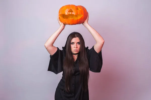 Young woman in Halloween witch costume in studio with yellow pumpkin. — Stock Photo, Image