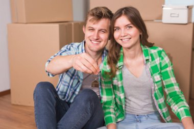 Mutlu genç çift kutuları yakın katta oturuyor. Genç aile yeni eve taşıdıktan. Kadın ve anahtarları gösterilen ve kameraya gülümseyen adam