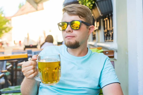 Adam bira içiyor. İçki bira açık kafede otururken yakışıklı genç adam — Stok fotoğraf