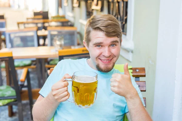 Люди, напої, алкоголь, жести і концепція дозвілля щасливий молодий чоловік п'є пиво і показує великі пальці вгору . — стокове фото