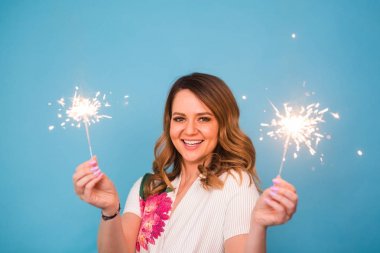 Kopya alanı ile mavi arka plan üzerinde bengal ışıklar holding mutlu bir kadın portresi. Noel, kutlamalar ve tatil kavramı