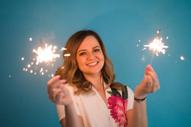 Kopya alanı ile mavi arka plan üzerinde bengal ışıklar holding mutlu bir kadın portresi. Noel, kutlamalar ve tatil kavramı