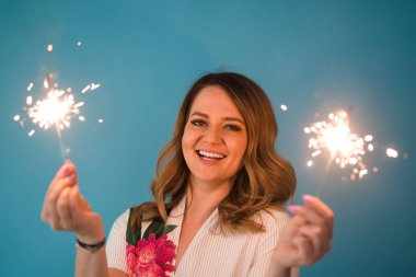 Kopya alanı ile mavi arka plan üzerinde bengal ışıklar holding mutlu bir kadın portresi. Noel, kutlamalar ve tatil kavramı