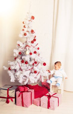 Bebek 1 yıl hediye kutusu ile Noel ağacı üzerinde oturan yaşlı. Mutlu Noeller. Tatil sezonu.