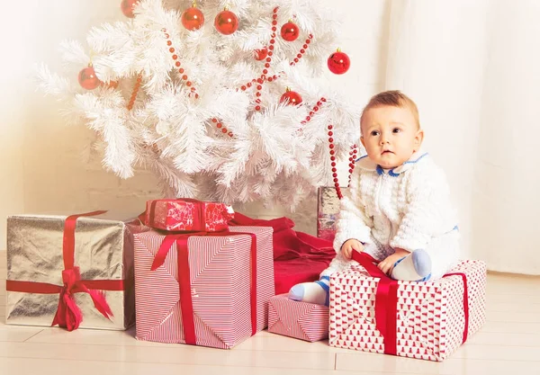 Dziecko 1 roku życia, siedzi na pudełko z choinki. Wesołych Świąt Bożego Narodzenia. Sezon wakacyjny. — Zdjęcie stockowe