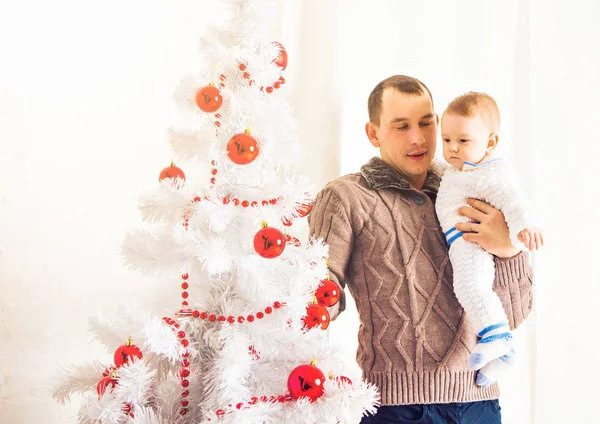 Gelukkig jonge vader spelen met zijn zoontje in de buurt van de kerstboom — Stockfoto