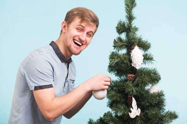 Boldog vicces ember díszíti a karácsonyfát a kék háttér. Ünnepség és az új évet koncepció. — Stock Fotó