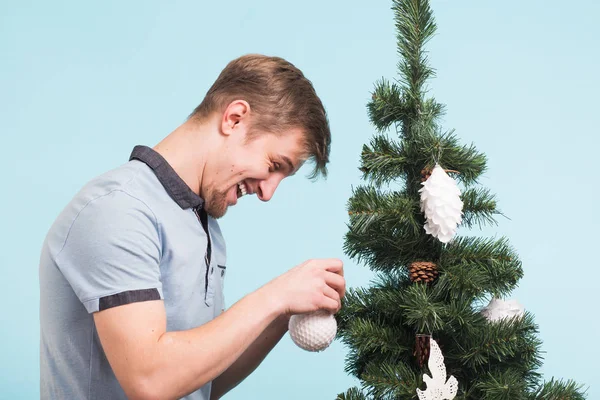 Glad rolig människa dekorera julgran på blå bakgrund. Fest och nyår koncept. — Stockfoto