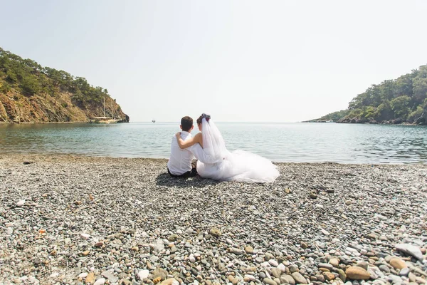 Jovem amor casamento casal sentado juntos na praia — Fotografia de Stock