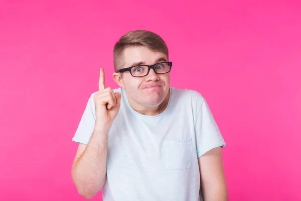 Uomo divertente con gli occhiali ha un'idea, puntando con il dito su sfondo rosa . — Foto Stock