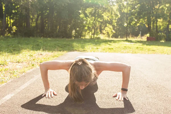 Mujer en forma joven haciendo ejercicio haciendo flexiones al aire libre — Foto de Stock