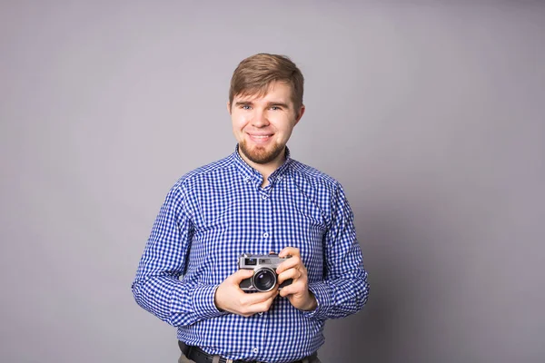 Νεαρή φωτογράφος άνθρωπος που κρατά κάμερας ρετρό σε ένα γκρίζο φόντο — Φωτογραφία Αρχείου