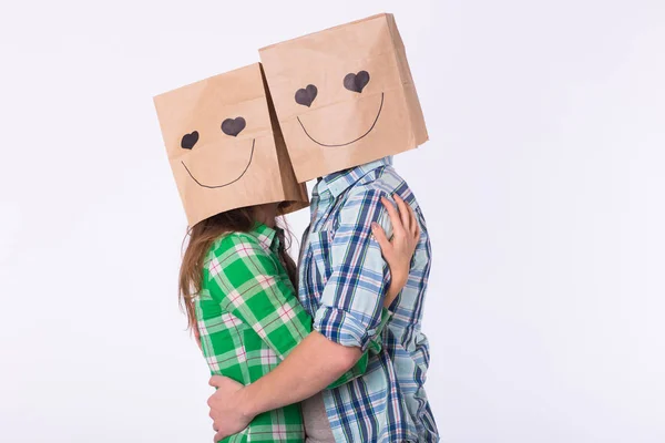 Влюбленная пара закрывает лицо бумажным пакетом на белом фоне — стоковое фото