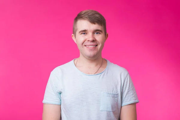 Engraçado jovem olhando para a câmera e sorrindo no fundo rosa . — Fotografia de Stock