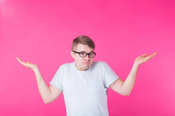 Ritratto di uomo confuso che mostra Non so gesto su sfondo rosa — Foto Stock