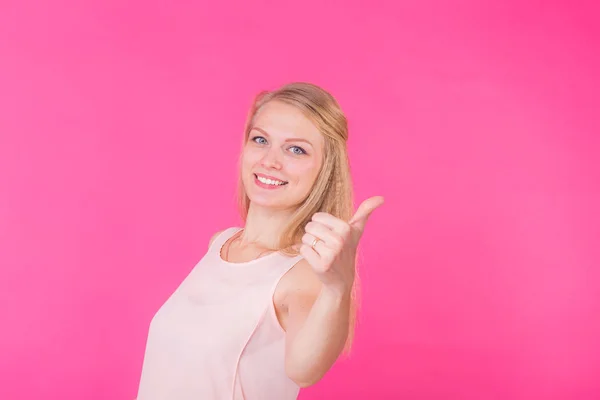 Emocionado chica feliz dando pulgares hacia arriba mostrando el éxito, aislado en el fondo rosa . — Foto de Stock