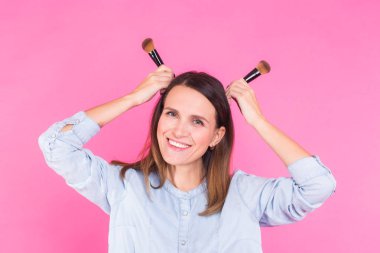 Pembe bir arka plan üzerinde fırçalar ile komik makyaj sanatçısı