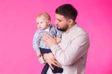Mutlu baba bebek oğlum elinde pembe bir arka plan üzerinde tutan.