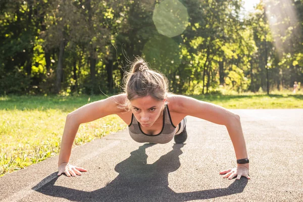 Mujer en forma joven haciendo ejercicio haciendo flexiones al aire libre —  Fotos de Stock