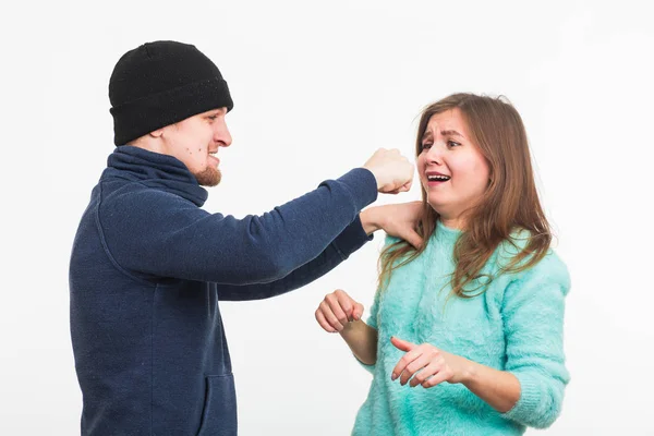 Donna vittima di violenza e abusi. Criminale uomo batte una donna su sfondo bianco — Foto Stock