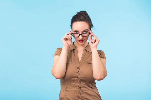 Elegante morena alegre en anteojos sonriendo a la cámara sobre fondo azul con espacio para copiar — Foto de Stock