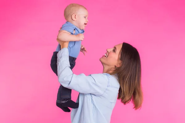 Happy young mother with a baby child on pink background — Stock Photo, Image